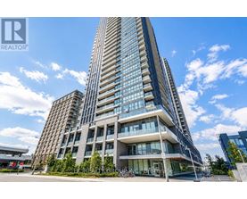 A tall building with a glass facade stands under a blue sky.