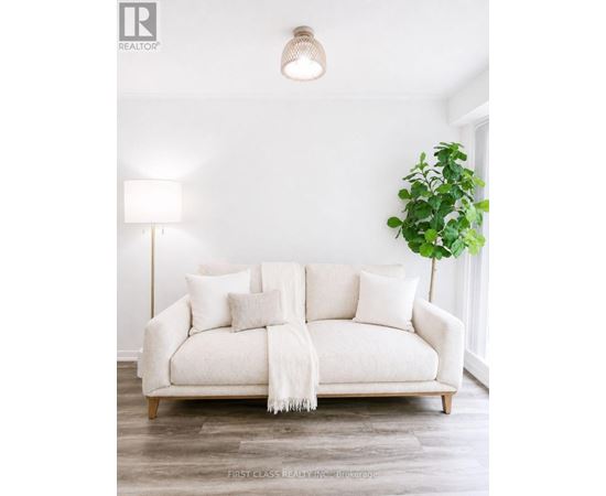 A white couch with a white blanket and pillows in a room.