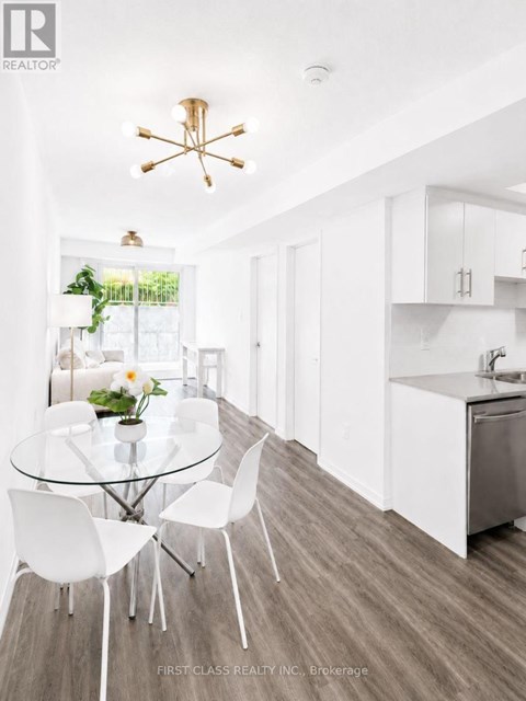 A modern kitchen with a glass table and white chairs.