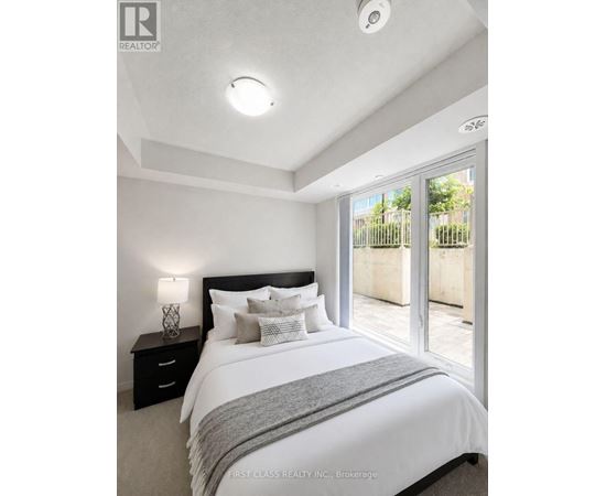 A bedroom with a large bed and a nightstand with a lamp.
