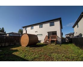 A wooden barrel is sitting on a grassy mound in front of a house.