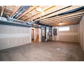 A spacious unfinished basement with concrete floors and exposed ceiling beams.