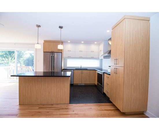 A modern kitchen with wooden cabinets and a black countertop.