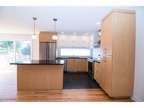 A modern kitchen with wooden cabinets and a black countertop.