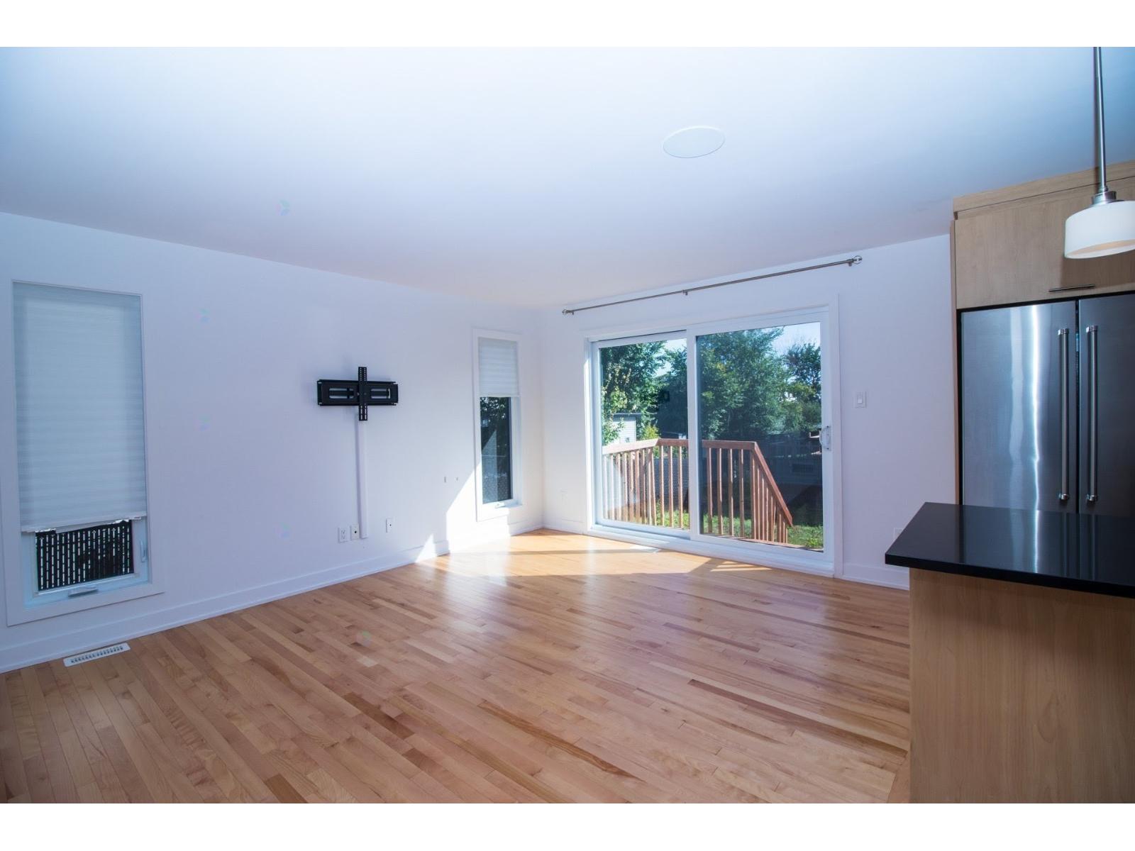 A room with wooden floors and a sliding glass door leading to a balcony.