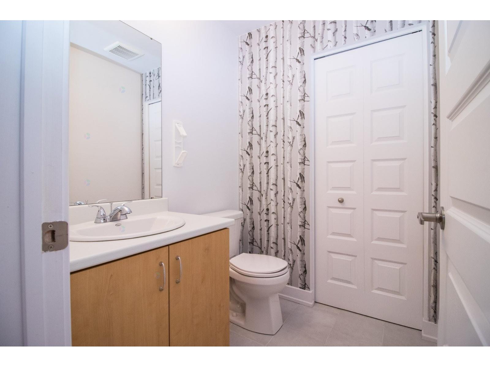 A white toilet sits in a bathroom next to a sink and a door.