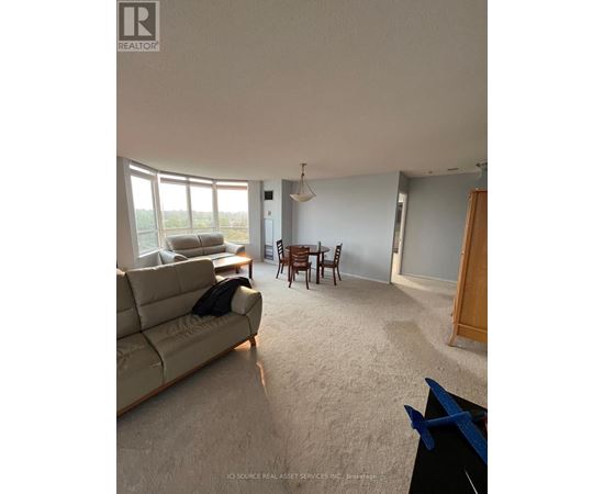 A living room with a couch, a table, and a dining table with chairs.