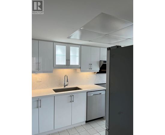 A kitchen with white cabinets and a black refrigerator.