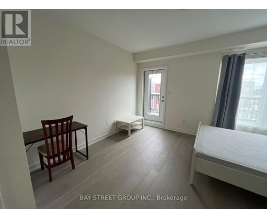 A bedroom with a bed, chair, and desk.