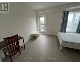 A bedroom with a bed, chair, and window.
