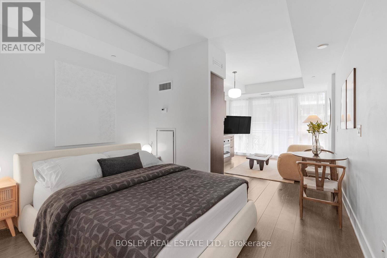 A bedroom with a large bed and a small table with a vase of flowers on it.