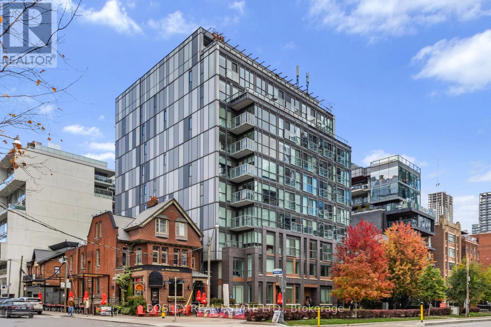 A modern glass building stands next to a traditional brick building.
