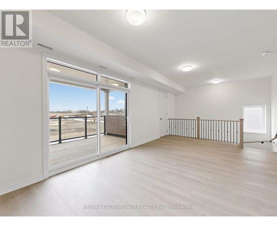 A spacious room with a sliding glass door leading to a balcony.