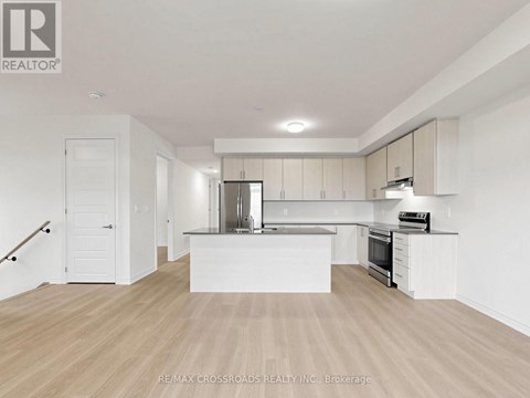 A spacious kitchen with white cabinets and a wooden floor.