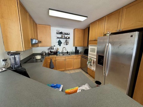 A kitchen with wooden cabinets and a stainless steel refrigerator.