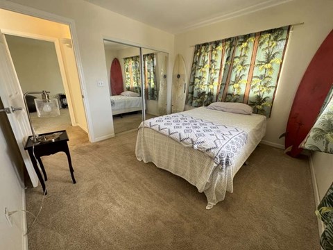 A bedroom with a large bed and a surfboard on the wall.