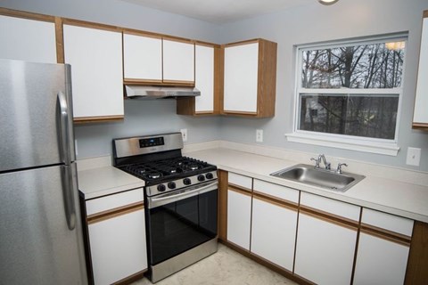 A kitchen with white cabinets and a stainless steel refrigerator.