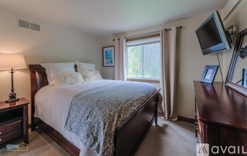 A bedroom with a large bed and a television on the wall.