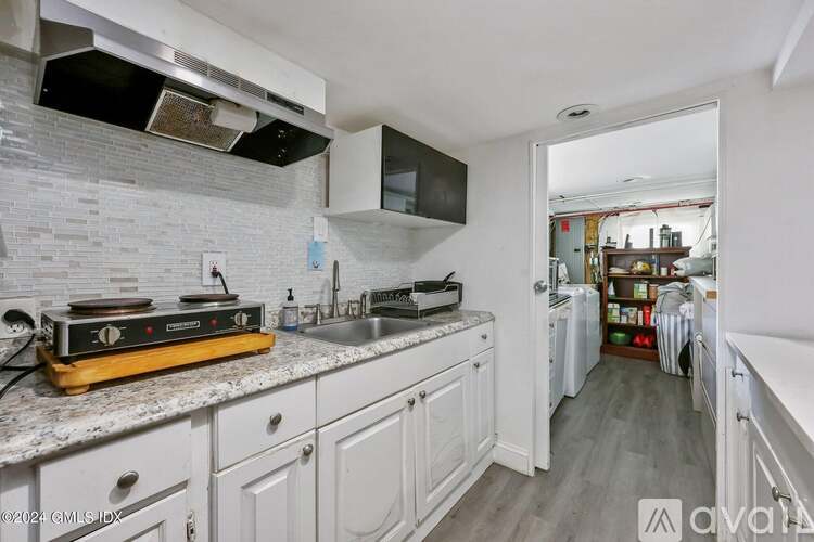 A kitchen with white cabinets and a marble countertop.