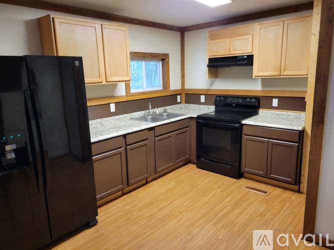 A kitchen with wooden cabinets and black appliances.