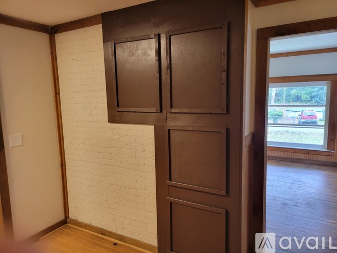 A room with a white brick wall and a brown door.