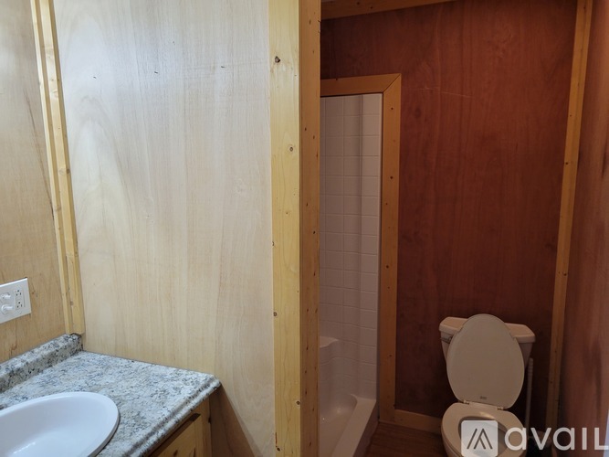 A bathroom with a toilet, sink, and wooden walls.