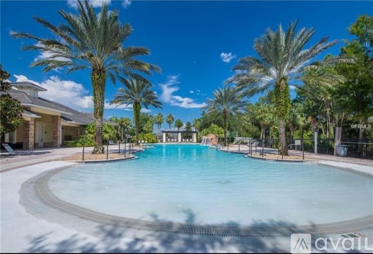 A large swimming pool surrounded by palm trees and a clear blue sky.