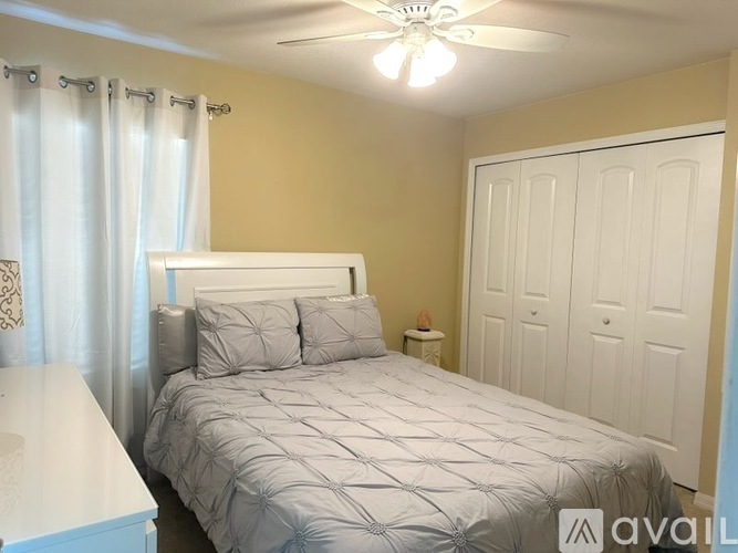 A bedroom with a bed, nightstand, and a ceiling fan.