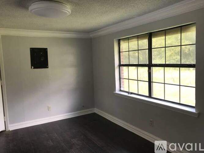 A room with a window and a light switch on the wall.