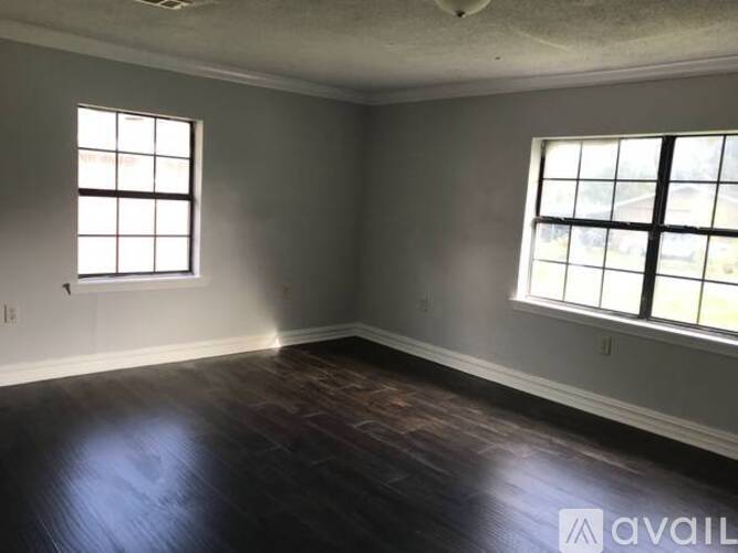 A room with two windows and wooden floors is available.