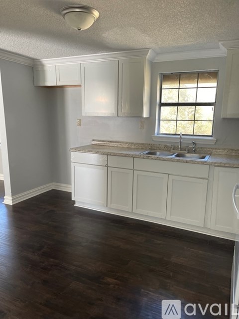 A kitchen with white cabinets and a window above the sink.