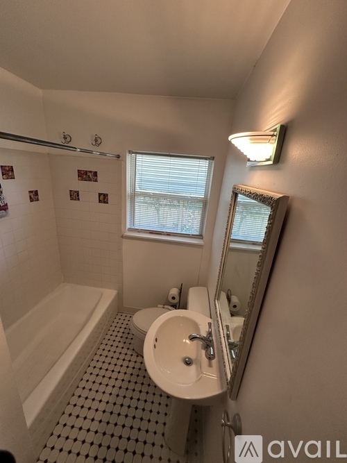 A bathroom with a white tub, sink, and tiled floor.