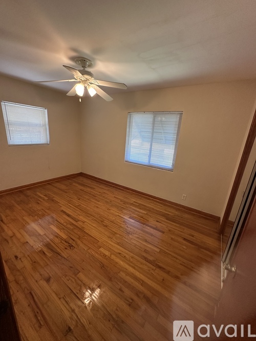 A room with wooden flooring and a ceiling fan.