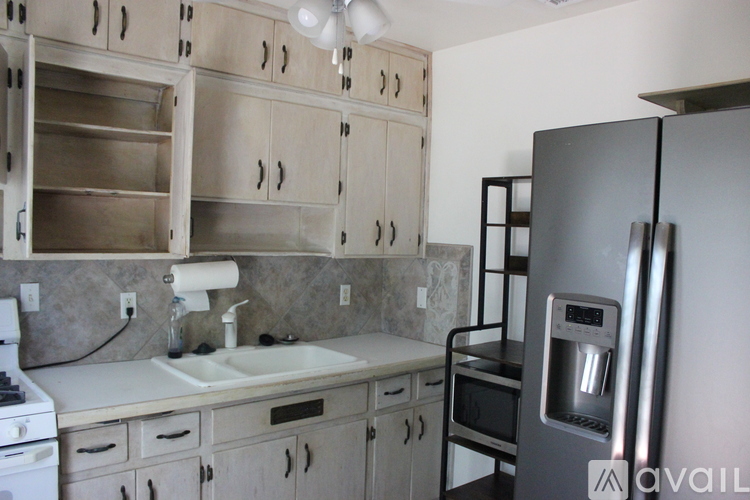 A kitchen with a refrigerator, sink, and cabinets.
