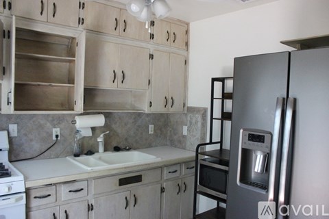 A kitchen with a refrigerator, sink, and cabinets.