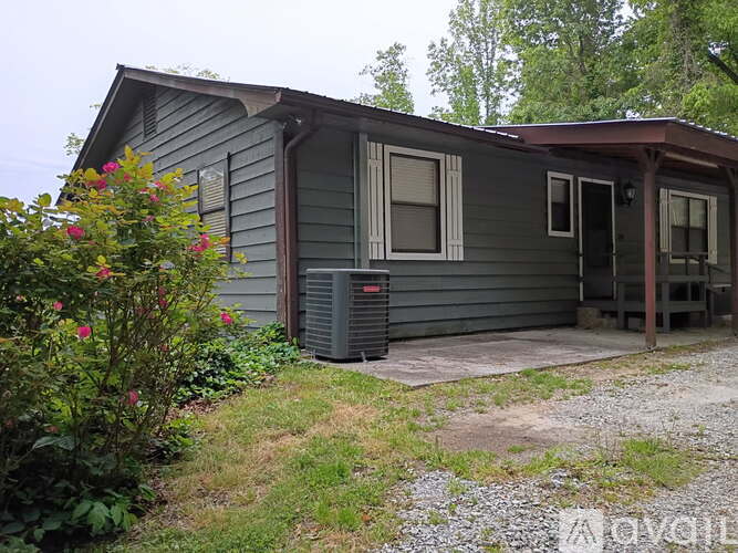 A house with a grey siding and a brown roof with a porch.