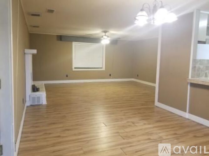 A spacious room with wooden flooring and white walls.