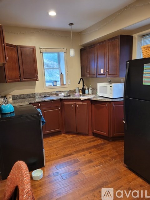 A kitchen with wooden cabinets and a black refrigerator.