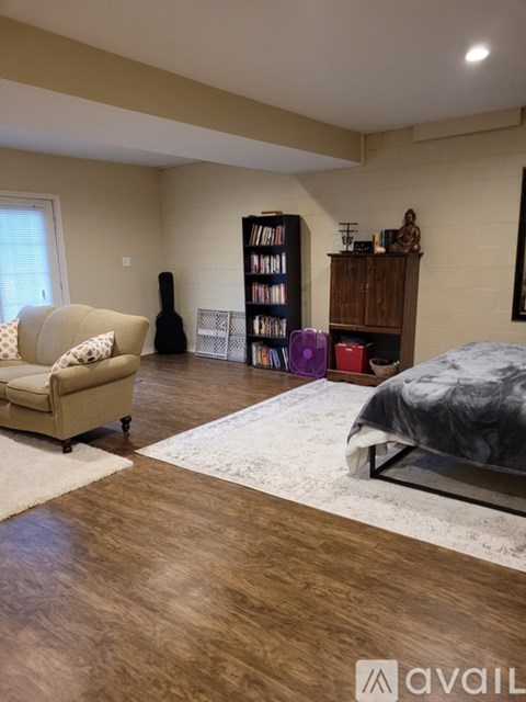 A living room with a couch, a bed, and a bookshelf.