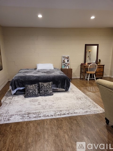 A bedroom with a bed, a chair, and a rug.