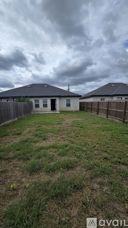 A backyard with a fence and a house in the background.
