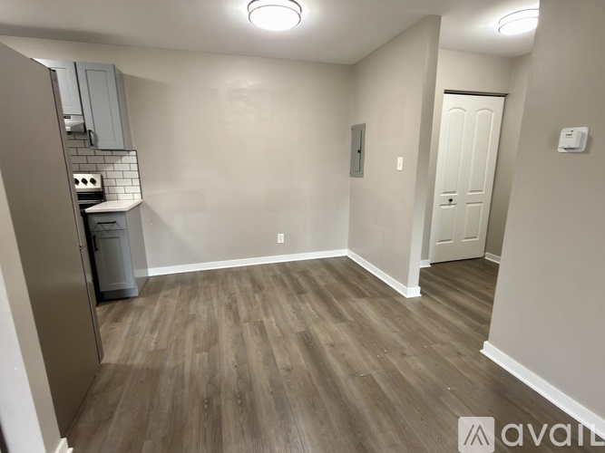 A room with wooden flooring and a small kitchenette.