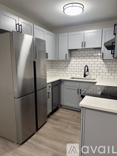 A kitchen with a refrigerator, cabinets, and a backsplash.