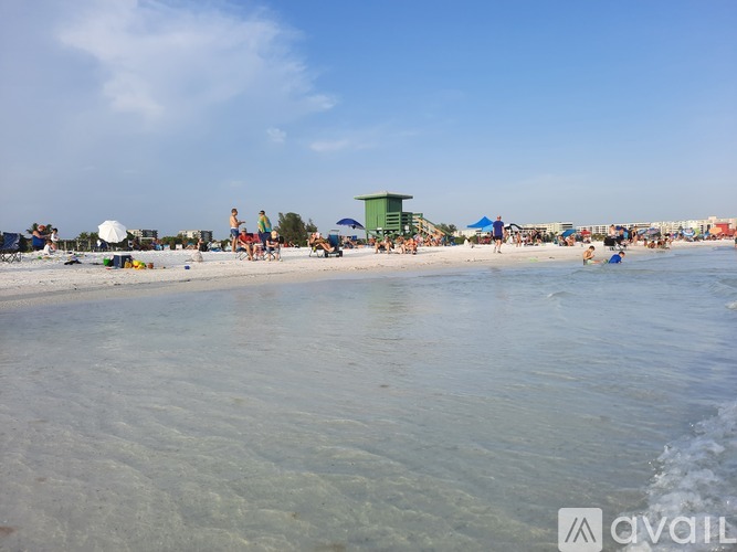 A beach scene with people and a green building in the distance.