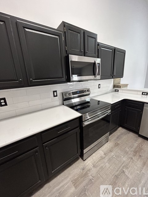 A kitchen with black cabinets and a white countertop.