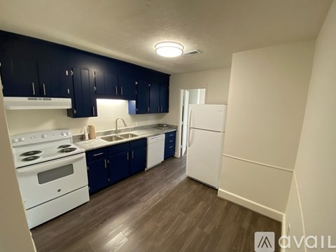 A kitchen with white appliances and dark blue cabinets.