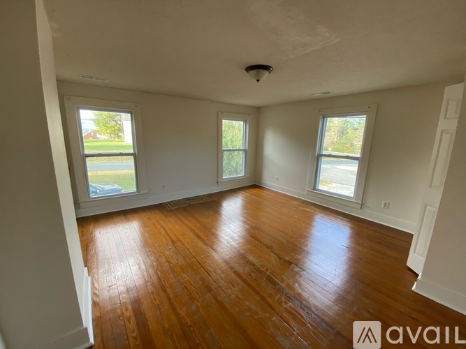 A room with wooden floors and three windows.