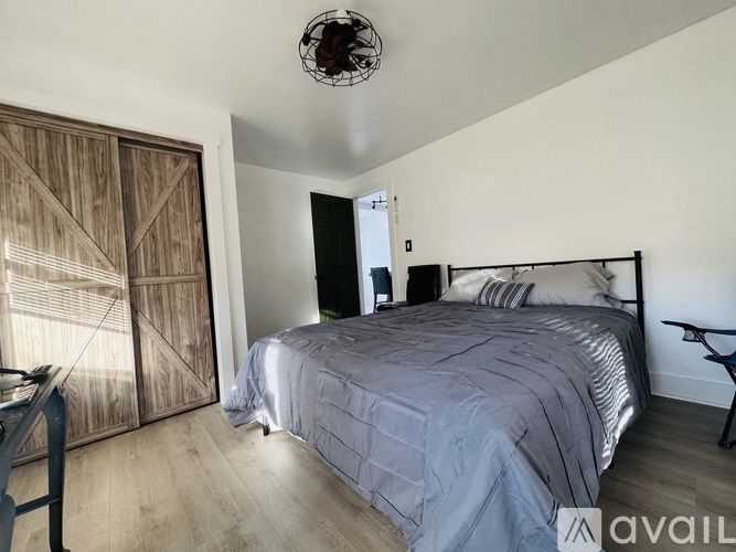 A bedroom with a bed, a ceiling fan, and a wooden door.