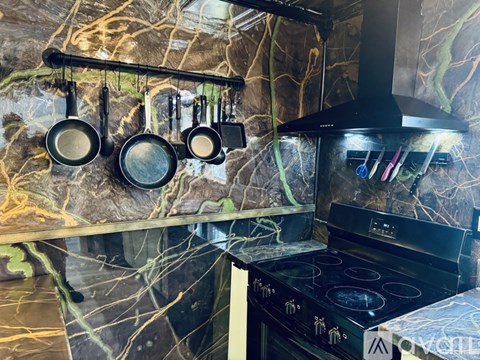 A kitchen with a black stove and hanging pots.