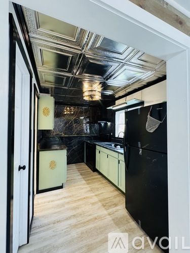 A kitchen with black appliances and wooden floors.